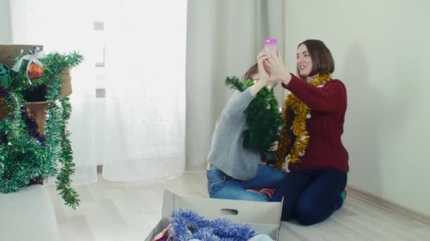 İki genç kız Noel ağacı eğleniyor selfie alarak süslemeleri için hazırlanıyor — Stok video