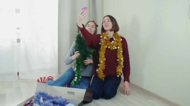 Dos jóvenes preparando el árbol de Navidad para las decoraciones tomando selfie divertirse — Vídeo de stock