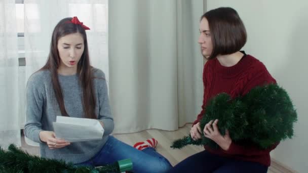 Two quarreling girls preparing Christmas tree for decorations — Αρχείο Βίντεο