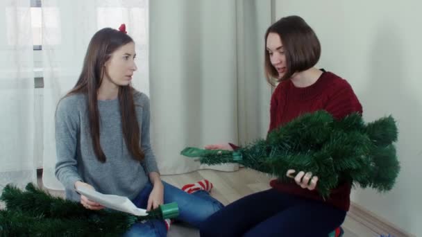 Two quarreling girls preparing Christmas tree for decorations — Stock video