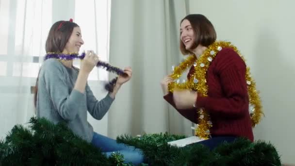 Dos muchacha joven que prepara el árbol de Navidad para adornamientos y que se divierten Nuevo año — Vídeos de Stock