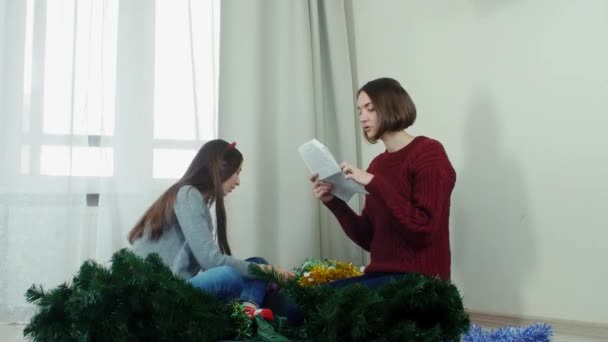 सजावटीसाठी ख्रिसमस ट्री तयार करणारी दोन तरुण मुलगी आणि नवीन वर्ष मजा — स्टॉक व्हिडिओ