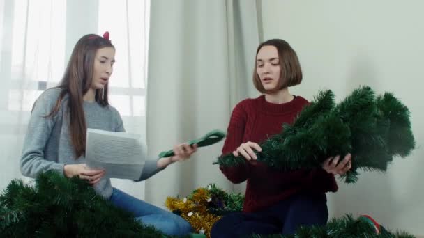 Dos muchacha joven que prepara el árbol de Navidad para adornamientos y que se divierten Nuevo año — Vídeo de stock