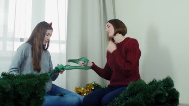 Две юные девушки готовят елку к украшениям и веселятся Новый год — стоковое видео