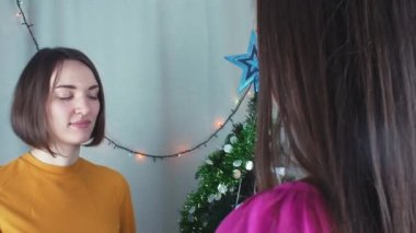 İki neşeli kız Noel veren t ve minnetle açmadan sunar