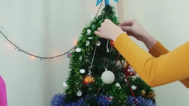 Dos mujeres jóvenes que adornan el árbol de Navidad La preparación de año nuevo que se divierten — Vídeos de Stock