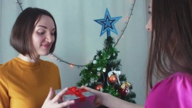 İki neşeli kız Noel veren t ve minnetle açmadan sunar