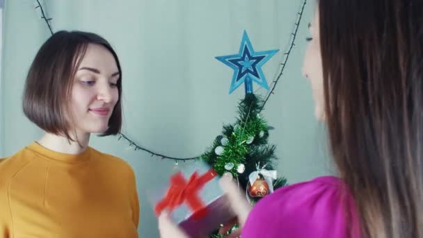 Dos chicas alegres dando regalos de Navidad abriéndolos con decepción — Vídeo de stock