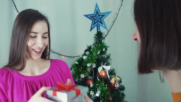 Dos chicas alegres dando regalos de Navidad abriéndolos con decepción — Vídeo de stock