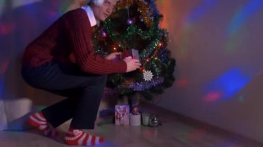 Noel ağacına sinsice ve bir hediye yerleştirerek genç adam