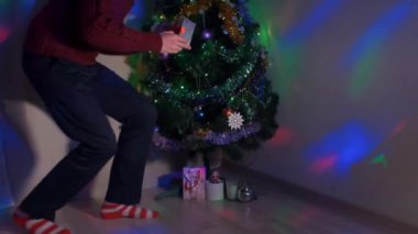 Noel ağacına sinsice ve bir hediye yerleştirerek genç adam
