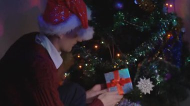 Noel ağacına sinsice ve bir hediye yerleştirerek genç adam