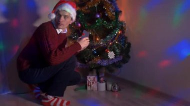 Noel ağacına sinsice ve bir hediye yerleştirerek genç adam