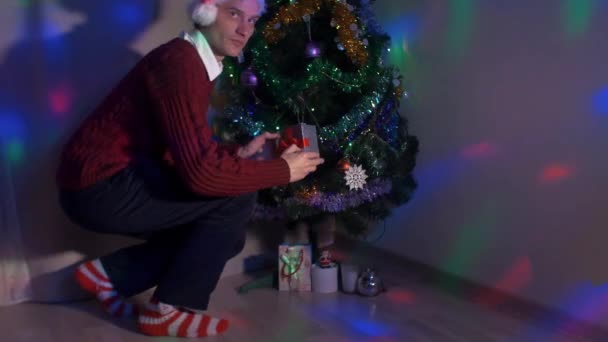 Jovem esgueirar-se para a árvore de Natal colocando presente desaparecer diante de seus olhos — Vídeo de Stock