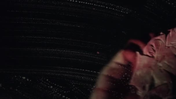 Bloedige hand een vensterglas met diepe donkere achtergrond van de bloedige lap afvegen — Stockvideo
