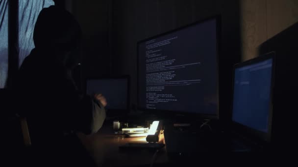 Hacker en código de craqueo de capucha usando computadoras en cuarto oscuro — Vídeo de stock