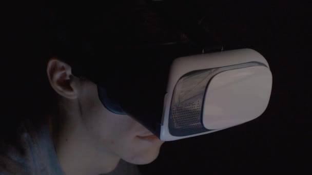 Молодой человек использует очки VR в темной комнате вблизи — стоковое видео