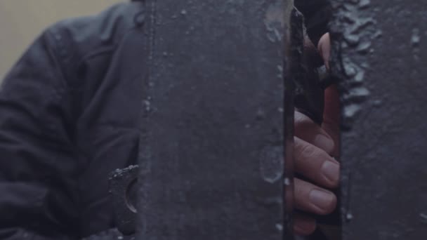 Młody człowiek ręka trzyma kłódkę na żelaznej bramy z bliska — Wideo stockowe