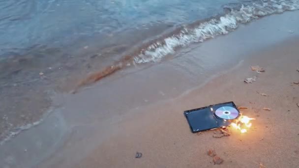 Datový disk cd v ohni na písku na pobřeží — Stock video