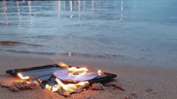 Disco cd dati in fiamme sulla sabbia a costa — Video Stock