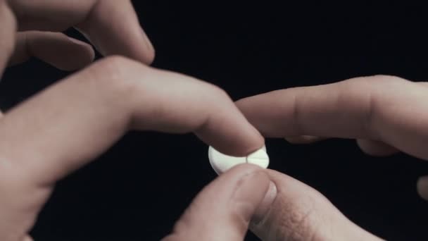 Homme examine petite pilule et grande pilule sur les mains gros plan fond noir POV 