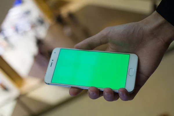 Erkek el ile alışveriş merkezi Yeşil perde smartphone kullanarak. Birçok insan, arka