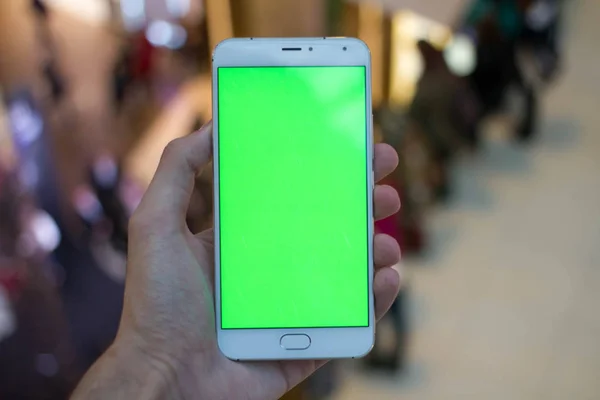 Erkek el ile alışveriş merkezi Yeşil perde smartphone kullanarak. Birçok insan, arka