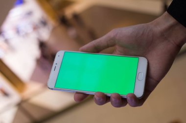 Erkek el ile alışveriş merkezi Yeşil perde smartphone kullanarak. Birçok insan, arka