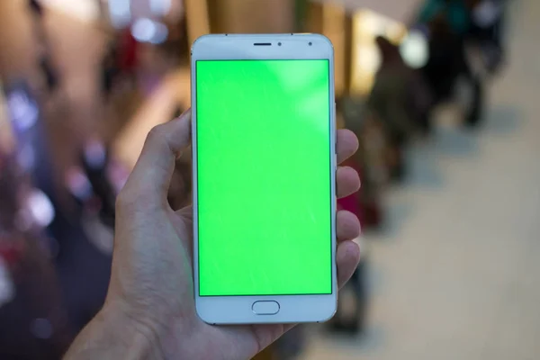 Mãos masculinas usando smartphone com tela verde no shopping center. Muita gente ao fundo. Fotos De Bancos De Imagens