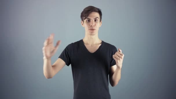 Hombre joven feliz en camisa negra sosteniendo el cartel verde de la hoja de la llave fondo gris — Vídeos de Stock