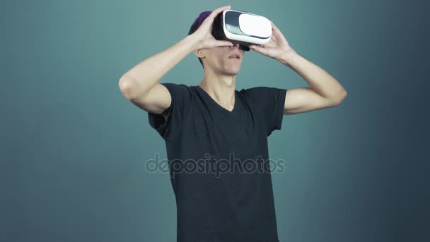 Mladý muž s fialovou ofinou pomocí vr brýle headset dělá gesta rozhlížel — Stock video