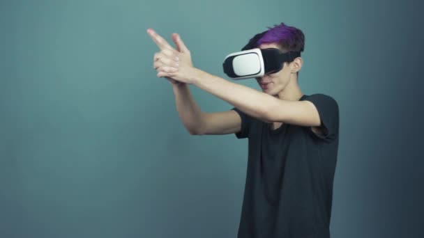 Young man with purple bangs using vr glasses headset doing gestures looking around — Stock Video