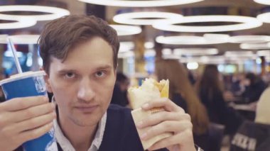 Genç erkek Shawarma rulo yemek ve alışveriş merkezi food court, kola içmek. Portre