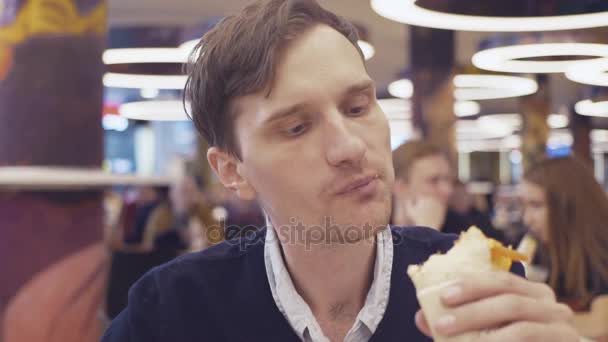 若い男性は、Shawarma ロールを食べるし、ショッピング モールのフードコートでコーラを飲みます。肖像画 — ストック動画