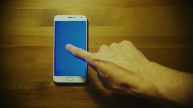 Erkek el dokunmatik ekran ve ahşap masa üzerinde mavi tuş ile beyaz smartphone srceen üzerinde dolar kazık atar
