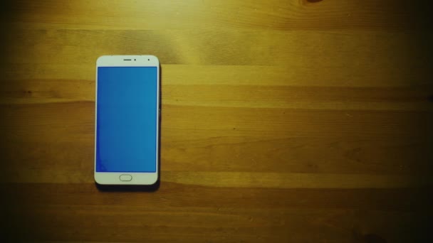 Mano maschile getta mucchio di dollari su srceen di smartphone bianco con chiave blu sul tavolo di legno — Video Stock