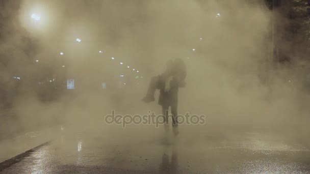Člověk nosit žena koryto bílé páry mrak na noční město ulice a polib ji — Stock video