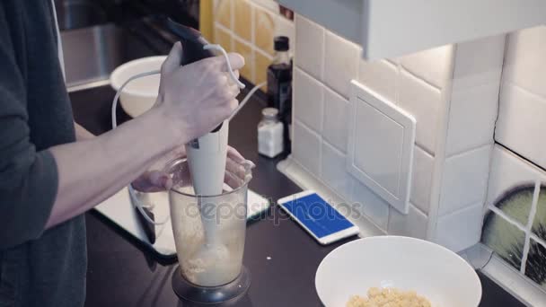 Young man preparing vegetable food at kitchen and watching video at smartphone — Stock Video