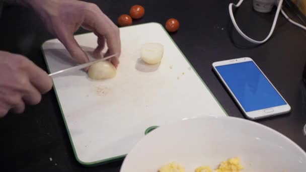 Manos masculinas cortando cebolla en la cocina casera. Joven preparando comida vegetal — Vídeos de Stock