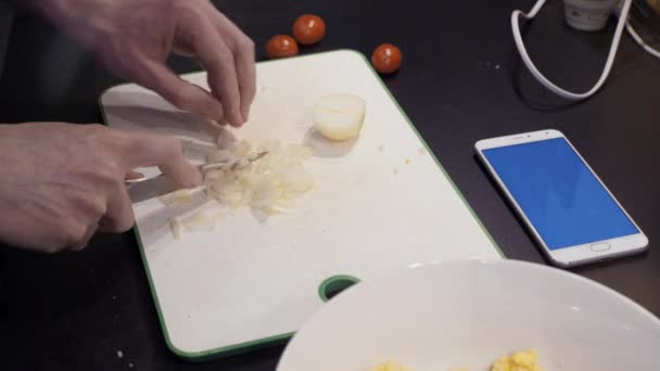Руки людини, що ріже цибулю на домашній кухні. Молодий чоловік готує здорову їжу — стокове відео