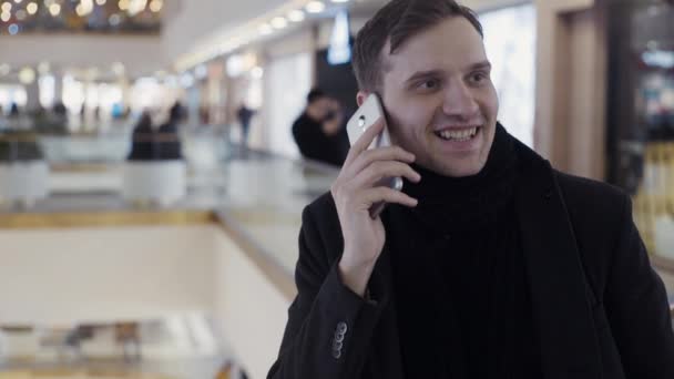 Kaukasische junge Männer, die in einem Einkaufszentrum ihr Smartphone benutzen. Porträt — Stockvideo