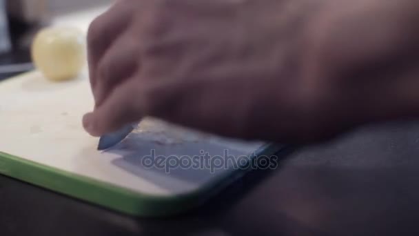 Mãos de jovem cortando cebola na cozinha. Jovem preparando comida vegetal — Vídeo de Stock