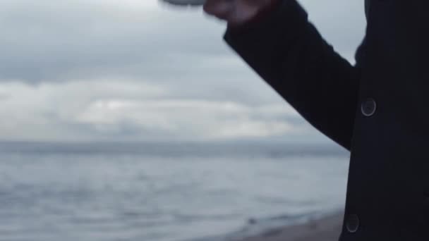 Fiatal férfi pohár a kezében állt a parton vihar felhők, a háttérben égő — Stock videók