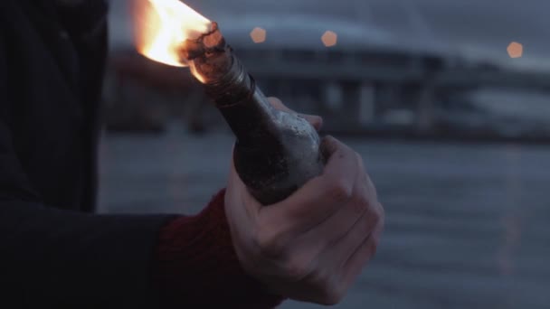 Mano del giovane stringendo bruciore bottiglia Molotov cocktail in piedi sulla costa — Video Stock