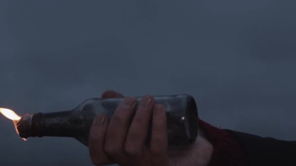 Main de jeune manifestant tenant une bouteille brûlante avec un cocktail Molotov 