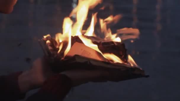 Jonge man leest brandende boek staande op kust storm wolken op achtergrond — Stockvideo