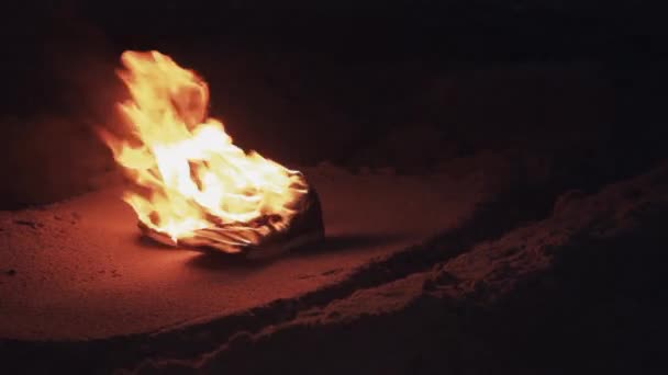 Bottes brûlantes sur le sable à la côte forte flamme brillante été nuit noire 