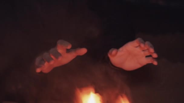 年轻男子的手座位附近的沙滩上燃烧的鞋子篝火 — 图库视频影像