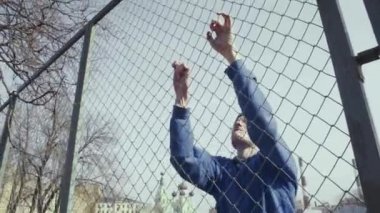 Genç adam bir metal çit tırmanma spor giyim