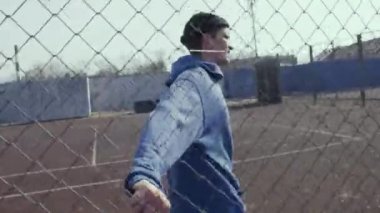 Bir spor alanı Metal tel çit dokunmadan saldırgan genç adam